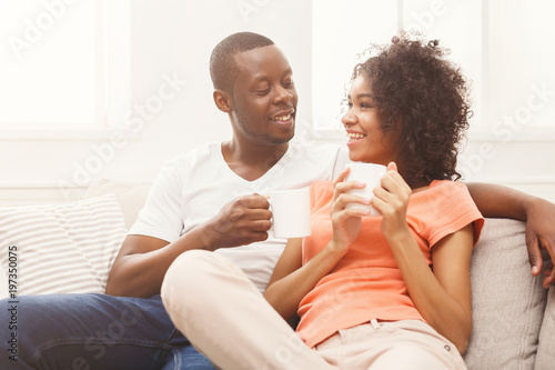 Smiling black couple drinking coffee at home