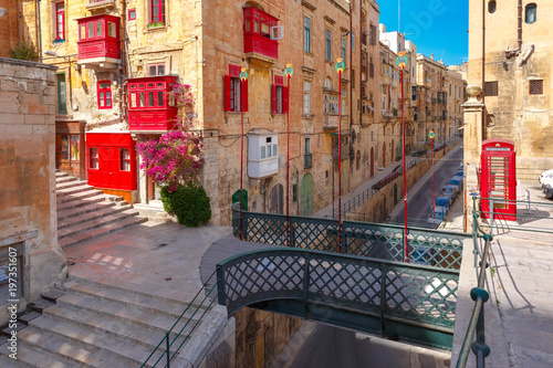 The traditional Maltese street with red phone box, shutters and balconies in Valletta, Capital city of Malta