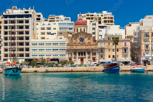 Quay of Silema with traditional Maltese church with red dome in the sunny day, Valletta, Capital city of Malta photo