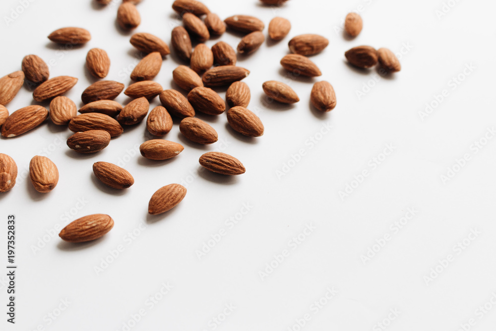 Obraz premium Pile of almonds on white background with copy space, healthy eating concept