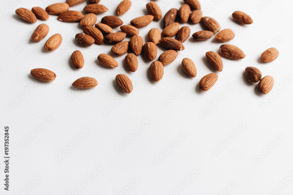 Pile of almonds on white background with copy space, healthy eating concept
