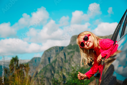 happy cute little girl travel by car in mountains