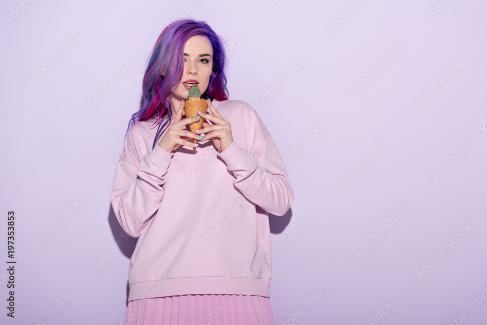 beautiful young woman in pink clothing licking cactus plant in waffle cone