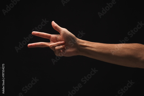 Male hand shows number three isolated at black