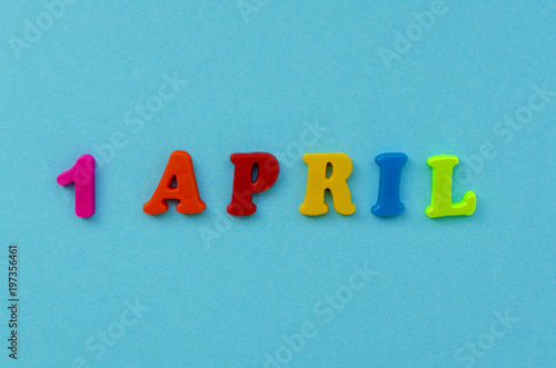 colorful text '1 april" of magnetic letters on blue paper background
