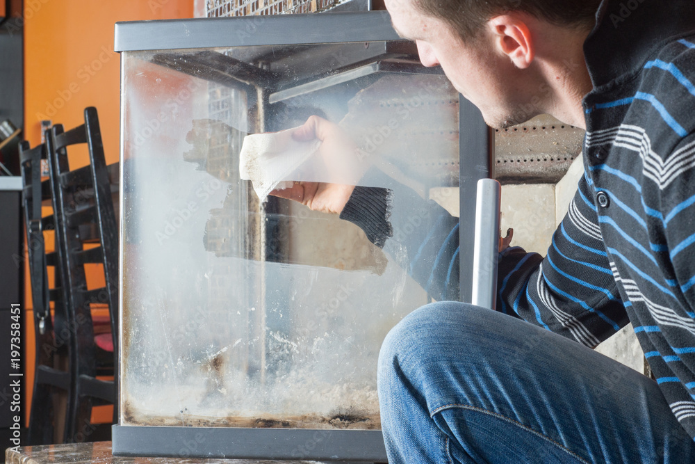 Man wipes the dirty glass of fireplace Man wipes the dirty glass of fireplace