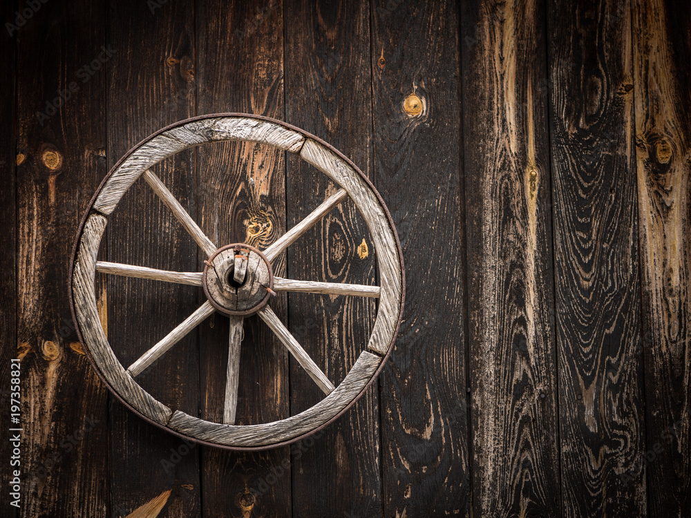 Old cartwheel hanging on a wooden barn Old cartwheel hanging on a wooden barn