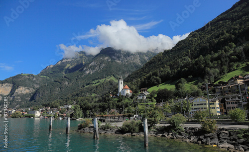 A church by Lake Lucerne with beautiful mountains and the emerald water of Lake Uri (Urnersee), one of the four basins of Lake Lucerne, and the surrounding mountains - Fluelen, Switzerland