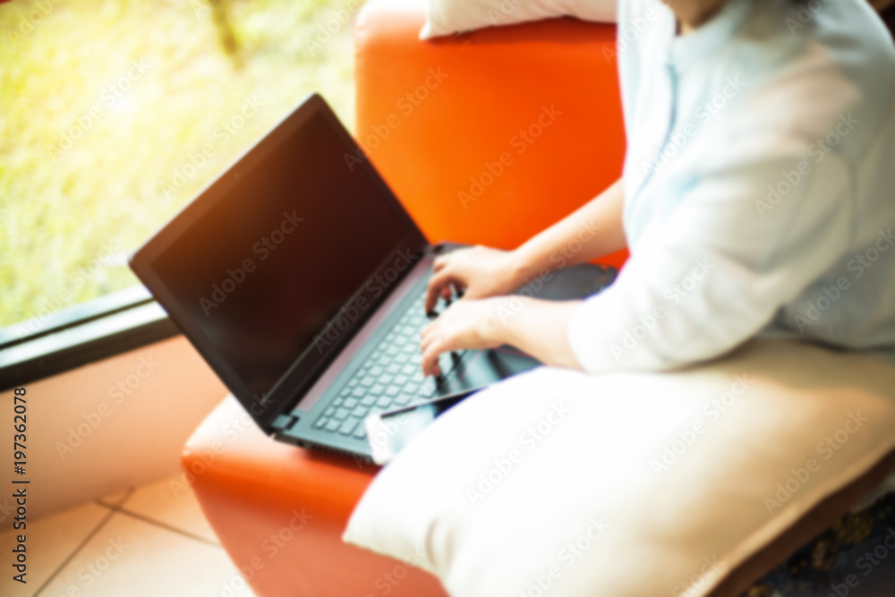 Fototapeta premium The blurry light design background of lady is using laptop for working and doing online business