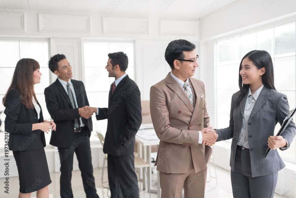 A confident business team of mixed ages and ethnicity making handshaking while meeting in a modern office. They are discussing ideas for their business development. A confident business team of mixed ages and ethnicity making handshaking while meeting in a modern office. They are discussing ideas for their business development.
