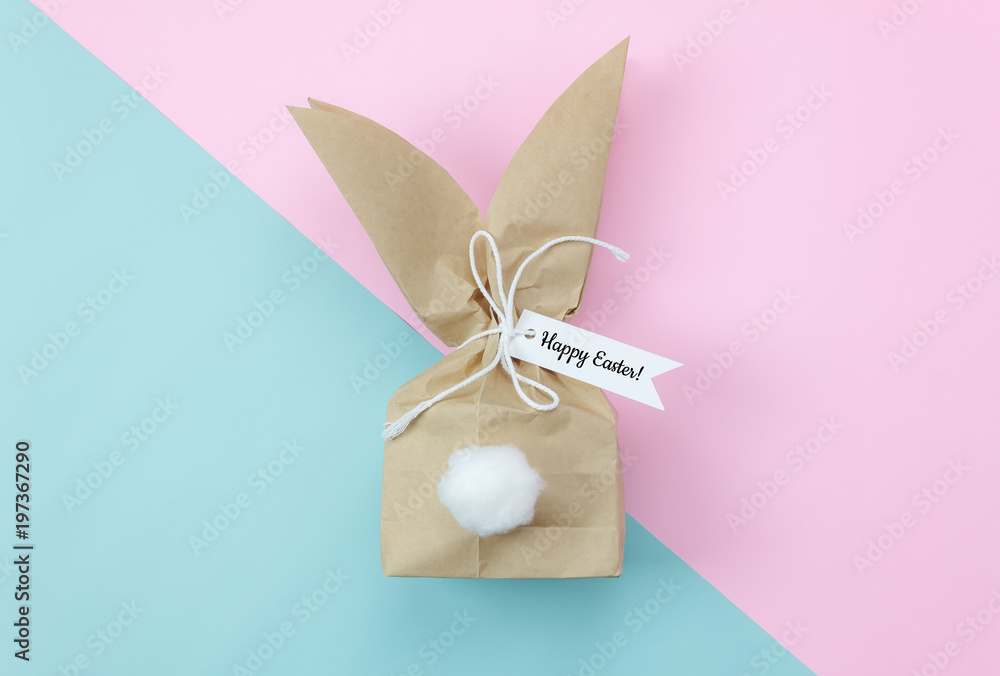Table top view shot of arrangement decorations Happy Easter holiday background concept.Flat lay beautiful bunny ear paper bag for gift on modern pink & blue paper at office desk.pastel tone design.