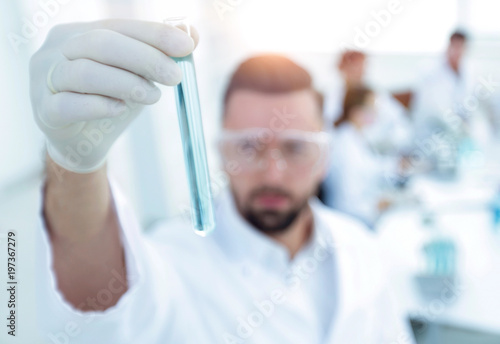 image is blurred. young scientist holding tube with the reagents