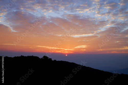 Sun rise purple orange sky background with landscape of mountain and tree with cloudy sky