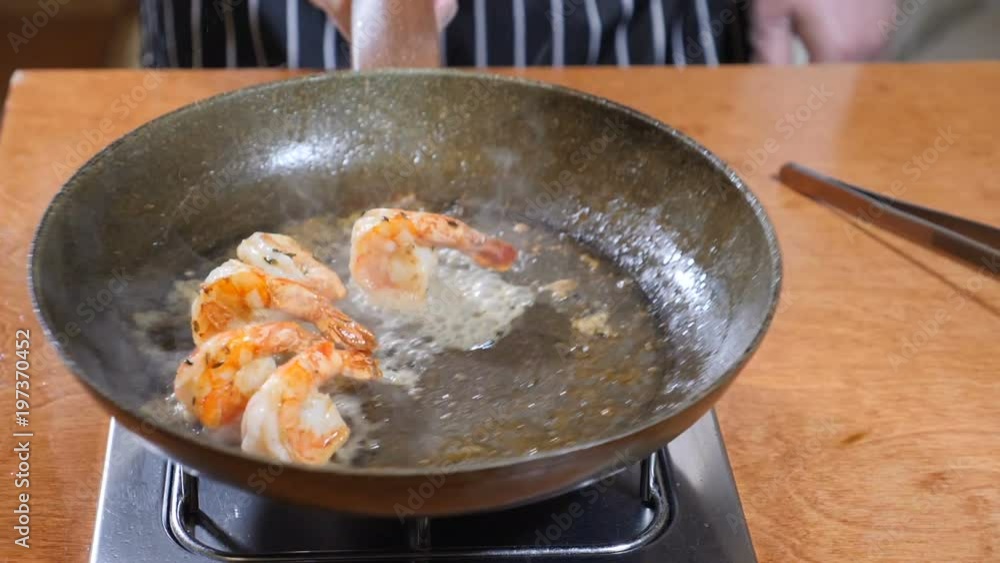 Close-up of a Chef Preparing Flambe Style Dish on a Pan. Slow motion. Oil and Alcohol Ignite with Open Flames. Stiring pan with tiger shrimp. Shot in 4k Close-up of a Chef Preparing Flambe Style Dish on a Pan. Slow motion. Oil and Alcohol Ignite with Open Flames. Stiring pan with tiger shrimp. Shot in 4k