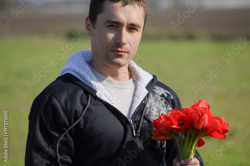 A man in a jacket on a field of tulips. Glade with tulips. photo