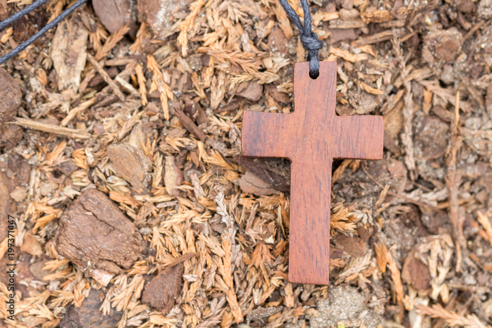 braunes Holzkreuz an einem Band am Boden liegend