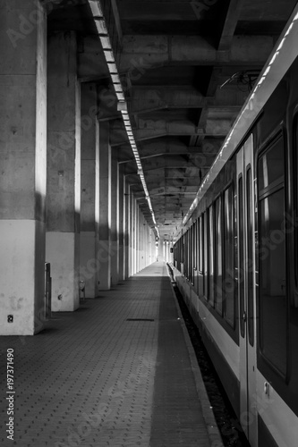 Railway station with train and platform, black and white. Illuminated platform of a covered railway station.