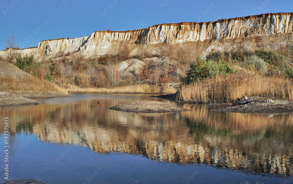 The cliffs of a canyon or quarry reflected in the lake The cliffs of a canyon or quarry reflected in the lake
