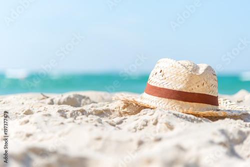 Summer Vacations. Hat of traveler on the sandy beach with blue sky background. Travel and Summer Concept