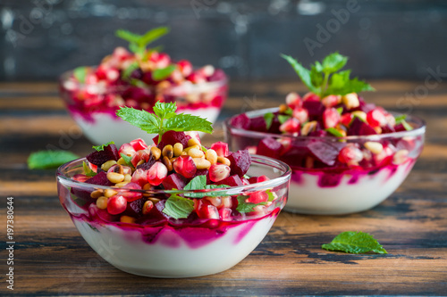 Healthy diet  salad with beets, fried pine nuts, fresh mint and Greek yogurt in small glass bowls on a wooden brown table.