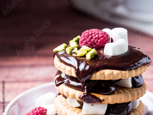 A sweet dessert of chocolate biscuit, raspberry marshmallow and a Cup of coffee on dark background. photo