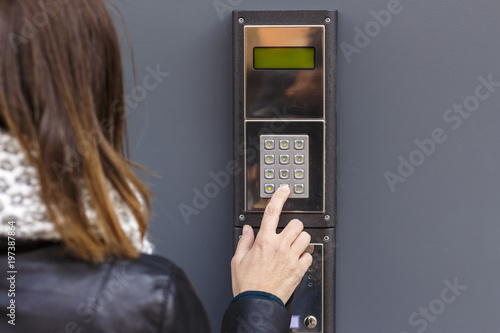 Woman pushing the button and talking on the intercom photo