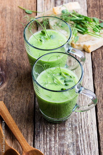 Green pea cream soup in glass mug with sprouts on top