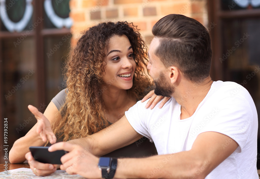 Happy loving couple using a smartphone sitting in terrace Happy loving couple using a smartphone sitting in terrace