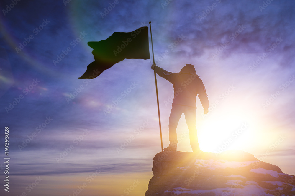 silhouette of man with flag of victory on top of a mountain over sky ...