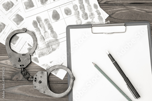 handcuffs with fingerprints on a wooden background. arrest. detention of a criminal. photo