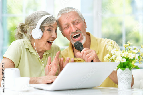 happy senior couple singing karaoke with laptop