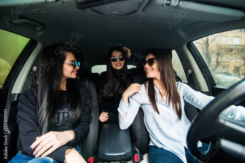 Just keep driving. Three beautiful young cheerful women looking away with smile while sitting in car