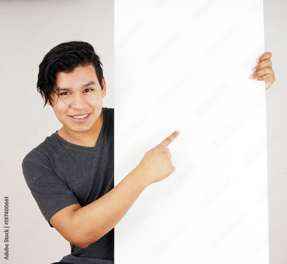 Young latino man pointing at blank sign Young latino man pointing at blank sign