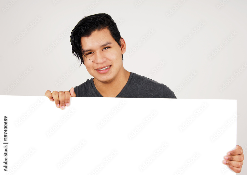 Friendly young latino man holding white sign Friendly young latino man holding white sign