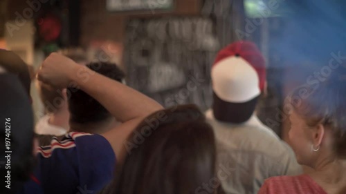 Football fans cheering while watching televised match at sports bar