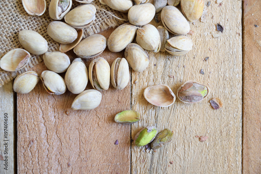 Pistachio nuts on a burlap fabric on a natural wooden table in a rustic kitchen. Empty copy space for Editor's text.