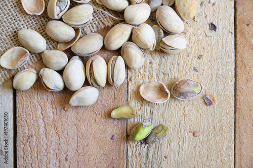 Pistachio nuts on a burlap fabric on a natural wooden table in a rustic kitchen. Empty copy space for Editor's text.