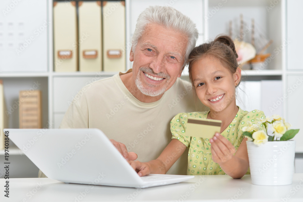Portrait of a grandfather and granddaughter using laptop together Portrait of a grandfather and granddaughter using laptop together