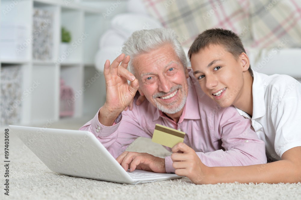 grandfather and grandson using laptop, grandson holding credit c grandfather and grandson using laptop, grandson holding credit c