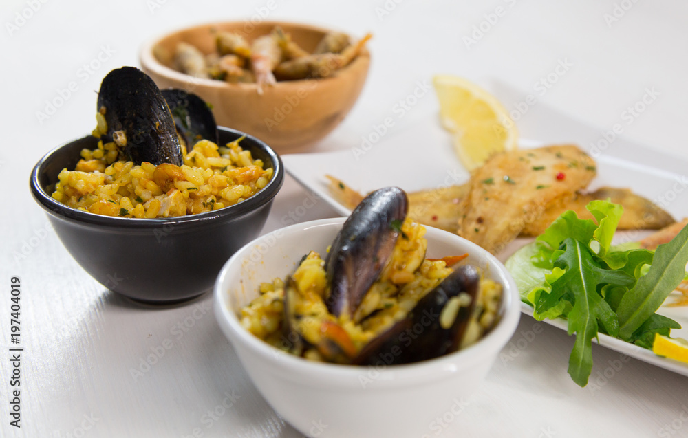 Fried fish and rice with mussels on dish with lemon and salad. Typical sicilian food