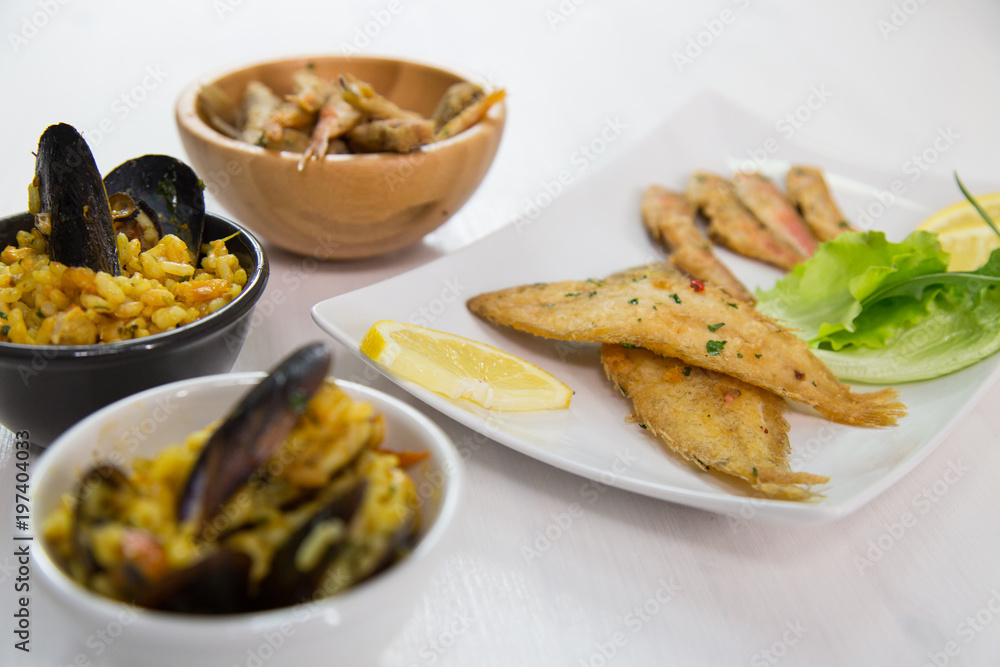 Fried fish and rice with mussels on dish with lemon and salad. Typical sicilian food Fried fish and rice with mussels on dish with lemon and salad. Typical sicilian food