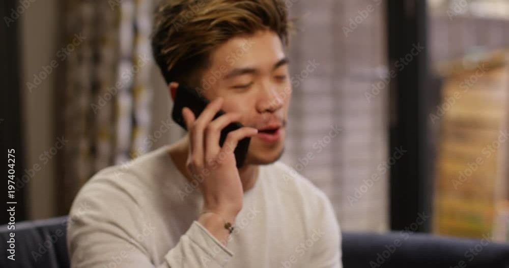 4K Camera pulls back from close up of cheerful Asian man talking on phone. Slow motion. 4K Camera pulls back from close up of cheerful Asian man talking on phone. Slow motion.