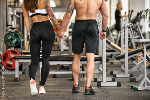 Back view of two young lovers in modern gym