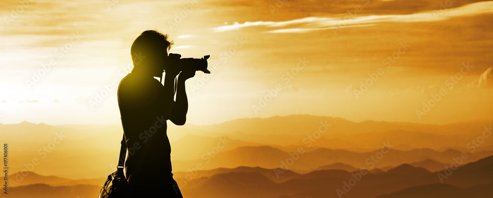 Silhouette of a backpacker photographer with mountains layer background during the sunset