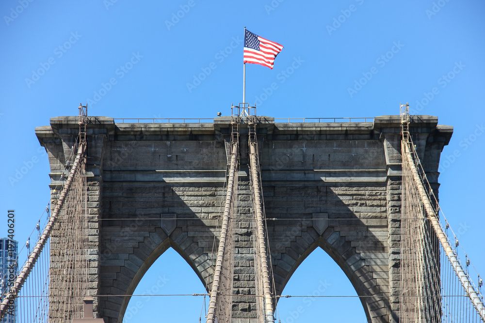 Fototapeta premium low angle view of flags on top of a bridge tower against clear blue sky