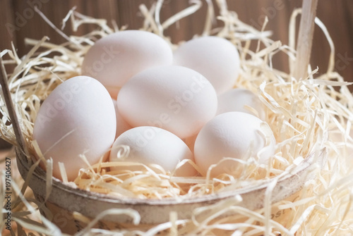 White eggs in a basket on straw