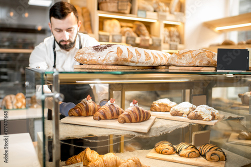 Seller putting delicious croissants on the store showcase of the bakery house Fototapet