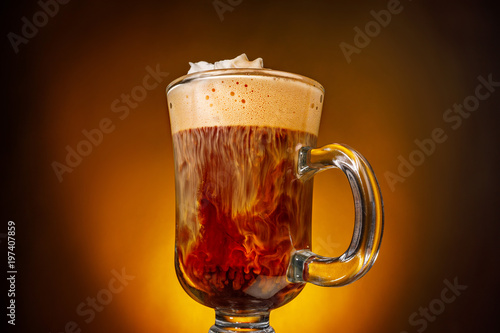стакан с кофе и сливками, которые смешиваются с кофе