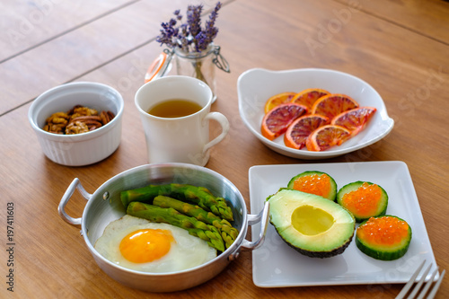 Table servie par les plat (oeuf, legumes, oeufs de saumon, noix, orange sanguine, thé vert). Repas type paleo, sans gluten, low carb.