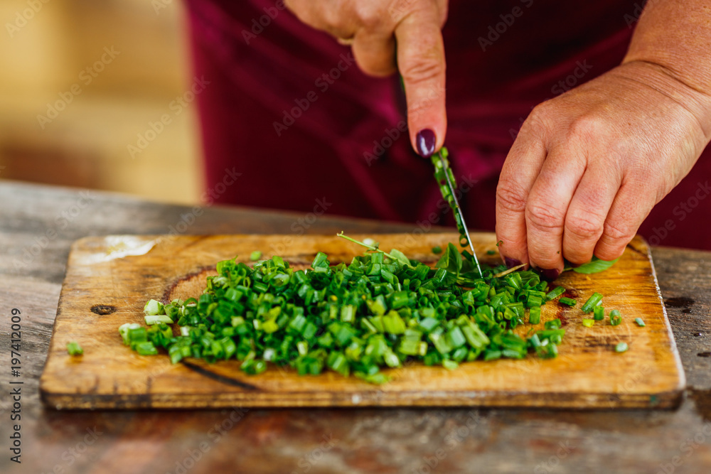 female chef cuts fresh green onion for salad female chef cuts fresh green onion for salad